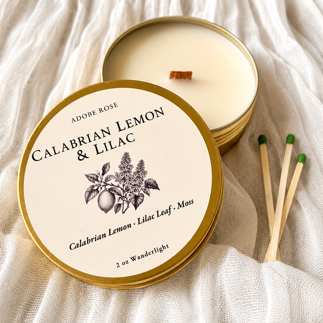 Candle in a tin with 'Calabrian Lemon & Lilac' label on a textured fabric background
