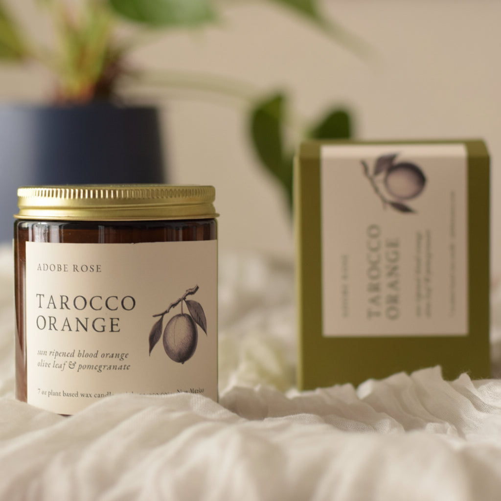 Jar of Tarocco Orange on a textured surface with a plant in the background
