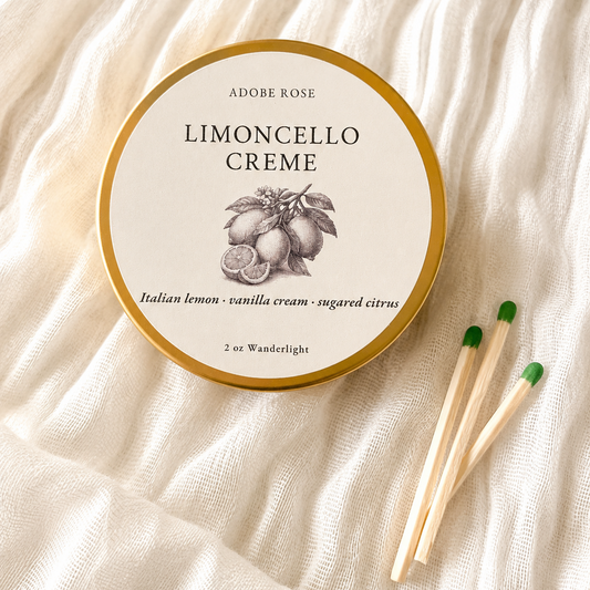 Adobe Rose Limoncello Creme container on a textured beige surface with matches beside it.