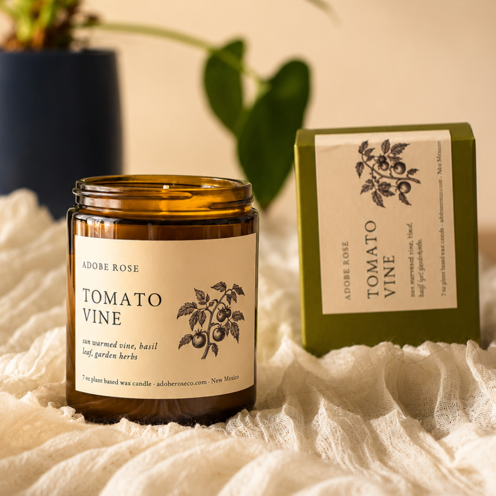 Candle labeled 'Tomato Vine' with packaging on a textured surface